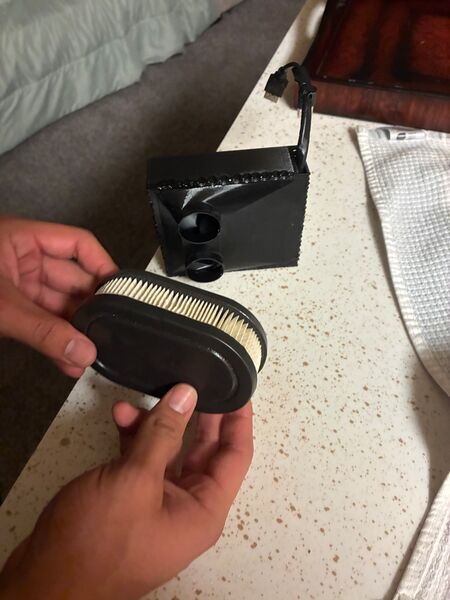 The pleated oval paper filter held apart from the printed body, showing the two round inlet ports and USB lead.